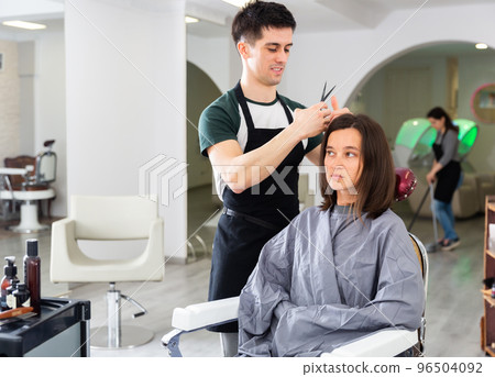 Man professional hairdresser cut female's hair in salon 96504092