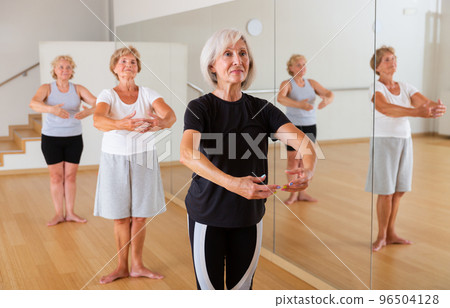 Elderly women practicing dance in the studio are standing in the 1st position of the ballet stand 96504128