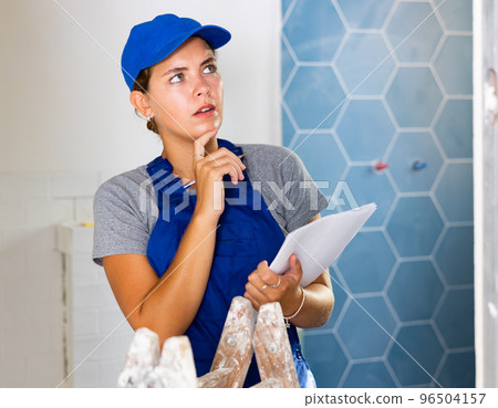 Young woman worker checks the number of tiles in the documents and makes notes Young woman worker checks the number of tiles in the documents and makes notes 96504157