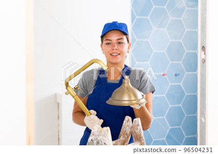 Young woman builder holds a shower head Young woman builder holds a shower head 96504231