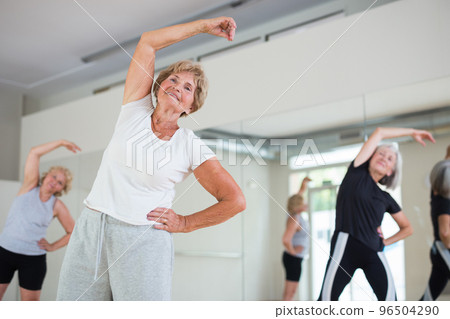 Senior lady with group of women doing stretching workout Senior lady with group of women doing stretching workout 96504290