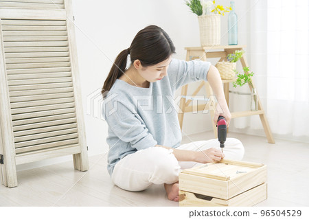 A woman doing DIY indoors using an electric screwdriver A woman doing DIY indoors using an electric screwdriver 96504529