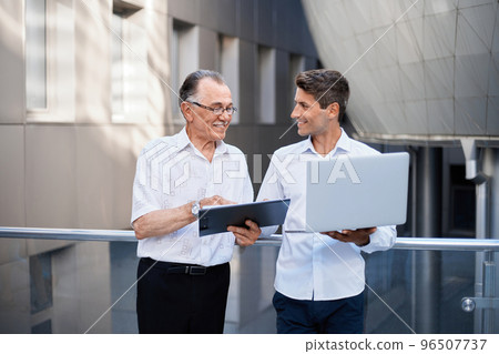 business colleagues with a laptop discussing a business document. business colleagues with a laptop discussing a business document. 96507737