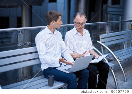 business colleagues with a laptop sitting at a bench in the business center . business colleagues with a laptop sitting at a bench in the business center . 96507739