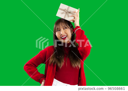 Merry Christmas. Young pretty asian woman in red sweater holding present box to celebrate Christmas and New Year party on green screen background. 96508661