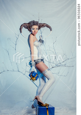 goat girl in suit snow maiden in the winter woods looks out from behind a tree goat girl in suit snow maiden in the winter woods looks out from behind a tree 96508884