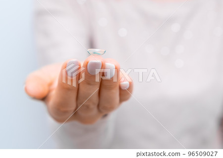 Close up woman holding eye lens on the tip of the finger Close up woman holding eye lens on the tip of the finger 96509027