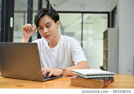 Smart Asian male concentrating doing his work project homework in campus library 96509638