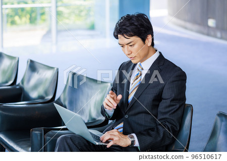 A man working on a laptop in a lobby chair 96510617