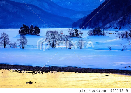 Lake Akimoto in winter with orange sunrise reflected on the surface of the lake (Urabandai, Fukushima Prefecture, March) 96511249