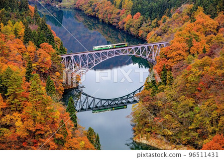 Tadami Line Train "Kiha 40 series + Kiha E120" crossing the first Tadami River bridge in autumn (Mishima Town, Fukushima Prefecture, November) 96511431