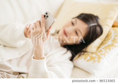 Woman watching smartphone on sofa Woman watching smartphone on sofa 96513865