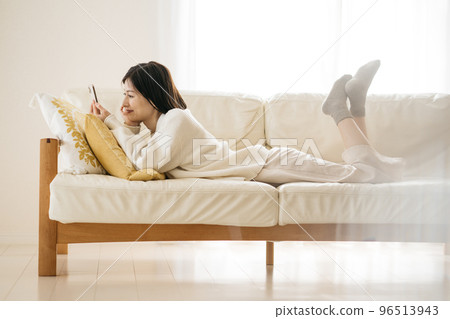 Woman watching smartphone on sofa 96513943