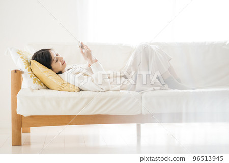 Woman watching smartphone on sofa 96513945