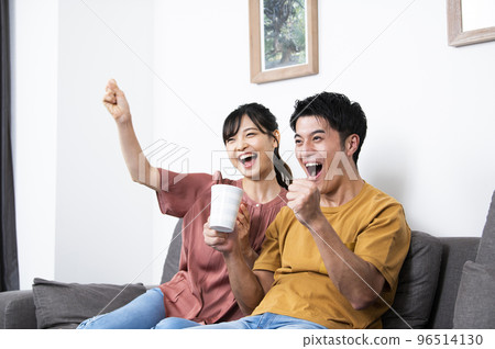 在電視上看體育節目的年輕夫婦 96514130