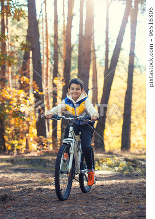 Happy kid boy having fun in autumn forest with a bicycle on beautiful fall day. Happy kid boy having fun in autumn forest with a bicycle on beautiful fall day. 96516306