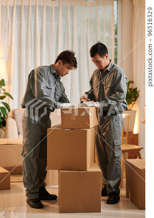 Team of movers packing and sealing cardboard boxes Team of movers packing and sealing cardboard boxes 96516329