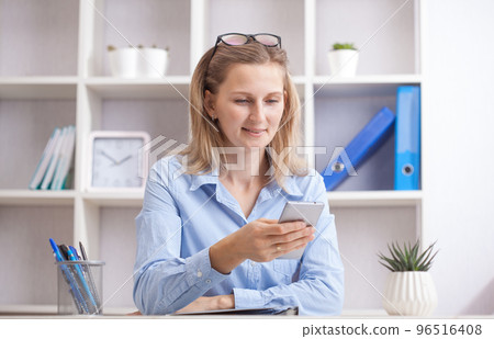 Young beautiful woman sitting in a chair and talking on the phone at her working place. Young beautiful woman sitting in a chair and talking on the phone at her working place. 96516408