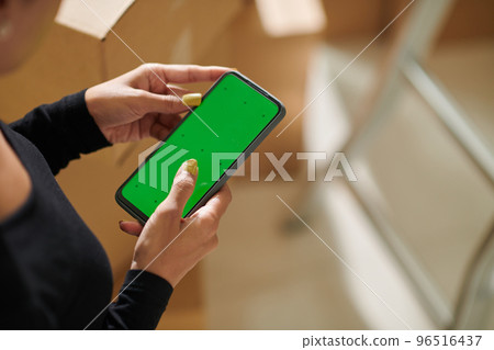 Woman checking application on smartphone with green screen 96516437
