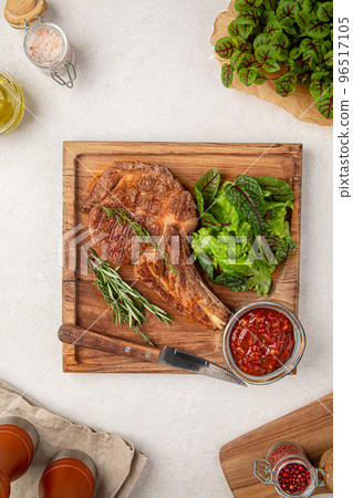 Portion of tomahawk steak with salad and sauce Portion of tomahawk steak with salad and sauce 96517105