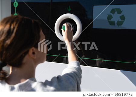 Woman uses a self service machine to receive used plastic bottles 96519772