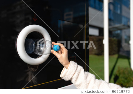 Woman uses a self service machine to receive used plastic bottles 96519773