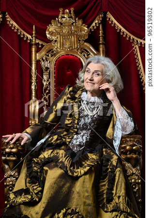 senior queen in a dress sits on a throne 96519802