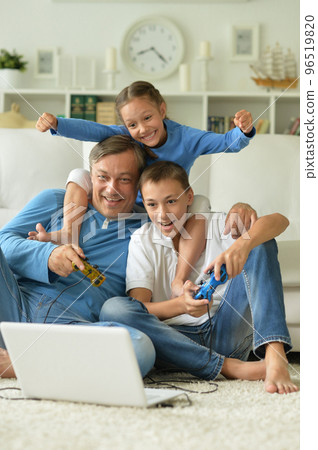 dad and kids have fun playing with a laptop  96519820