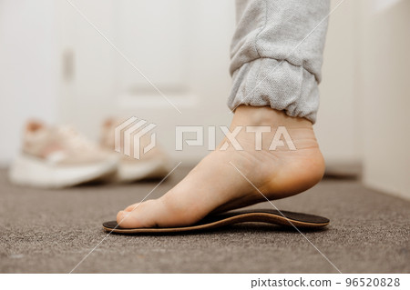 Flat feet diagnosis and orthotics, shoe inserts. Problems with flatfoot, pain. Identification of flat foot. Treatment to plantar fasciitis. Womans foot and insoles at home, close up view. Flat feet diagnosis and orthotics, shoe inserts. Problems with flatfoot, pain. Identification of flat foot. Treatment to plantar fasciitis. Womans foot and insoles at home, close up view. 96520828