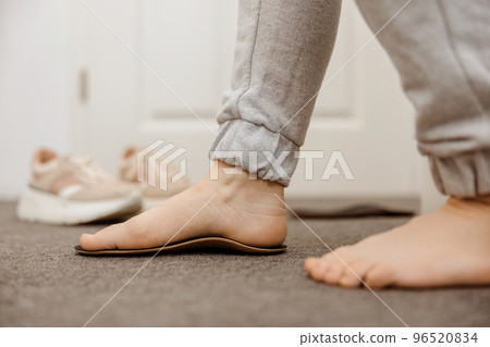Flat feet diagnosis and orthotics, shoe inserts. Problems with flatfoot, pain. Identification of flat foot. Treatment to plantar fasciitis. Womans foot and insoles at home, close up view. 96520834