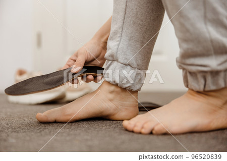 Flat feet diagnosis and orthotics, shoe inserts. Problems with flatfoot, pain. Identification of flat foot. Treatment to plantar fasciitis. Womans foot and insoles at home, close up view. 96520839