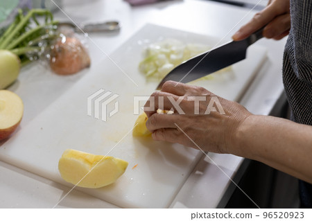 Hands of a woman cutting onions and apples in the kitchen Hands of a woman cutting onions and apples in the kitchen 96520923
