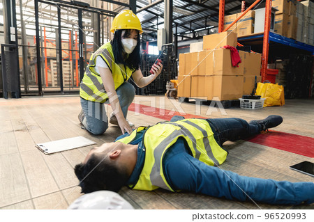 A female warehouse worker using a walkie-talkie called the factory's first aid team to rescue an unconscious man. pass out or blackout, unsafe, emergency 96520993