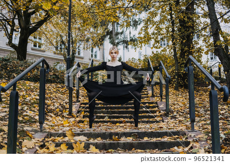 Ballerina Dancing in autumn city street, Modern Ballet Dancer in black dress, Pointe Shoes outdoors. Ballerina stretches, daily ballet stretching routine 96521341