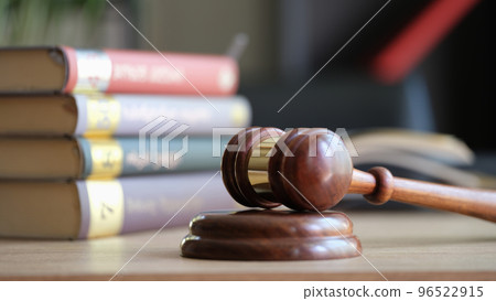 Judge gavel or hammer on sounding block and stack of law books on table 96522915