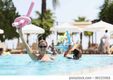 Smiling woman in sunglasses holding pink flexible sticks for aerobics Smiling woman in sunglasses holding pink flexible sticks for aerobics 96523068