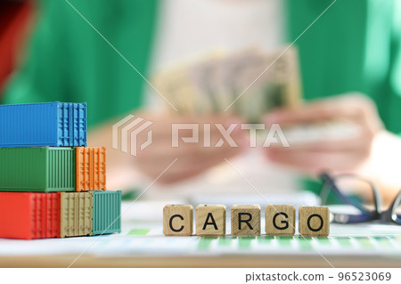 Cargo containers with word cargo and blurry man counting money in background Cargo containers with word cargo and blurry man counting money in background 96523069