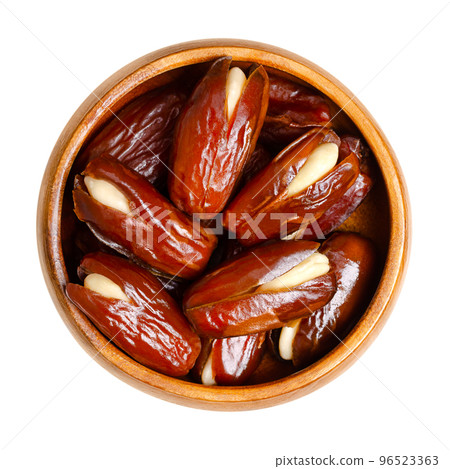 Almond-stuffed dates, in a wooden bowl. Sun dried Deglet Nour dates, cut open and pitted, then filled with whole blanched almonds. A delicious sweet snack or dessert, originally from North Africa. Almond-stuffed dates, in a wooden bowl. Sun dried Deglet Nour dates, cut open and pitted, then filled with whole blanched almonds. A delicious sweet snack or dessert, originally from North Africa. 96523363