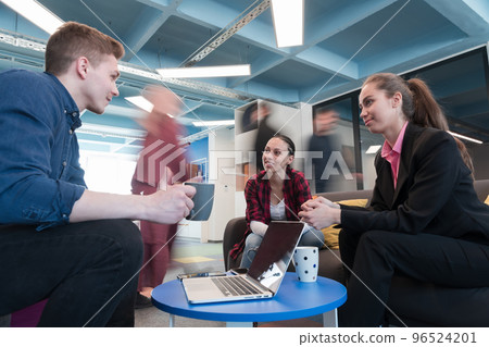 Multiethnic startup business team on meeting in a modern bright open space coworking office. Brainstorming, working on laptop. Group of coworkers walking around in motion blur. 96524201