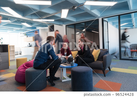 Multiethnic startup business team on meeting in a modern bright open space coworking office. Brainstorming, working on laptop. Group of coworkers walking around in motion blur. 96524428