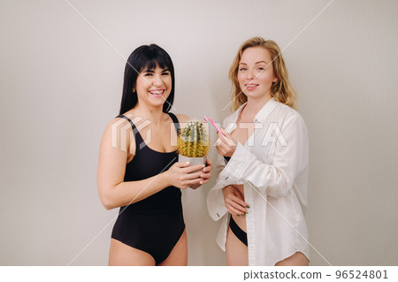Cactus concept. Unshaven body . One girl is holding a cactus in her hands, and the second girl is holding a razor. Symbol of unshaven body parts Cactus concept. Unshaven body . One girl is holding a cactus in her hands, and the second girl is holding a razor. Symbol of unshaven body parts 96524801
