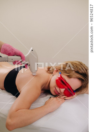 A girl in black underwear does laser hair removal on her back in the salon 96524817