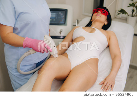 A cosmetologist performs a laser hair removal procedure in the office A cosmetologist performs a laser hair removal procedure in the office 96524903