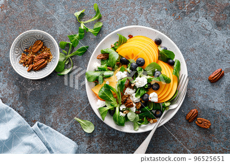 Persimmon fruit salad with blueberry, pecan nuts and ricotta chesse. Healthy food. Top view 96525651