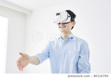 A man shaking hands with VR goggles at home 96526760