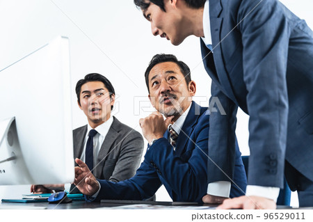 商人一邊看電腦屏幕一邊開會 商人一邊看電腦屏幕一邊開會 96529011