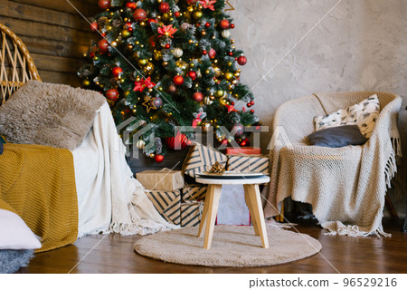 Christmas gifts lie on a stool near a Christmas tree in the interior of a country house 96529216