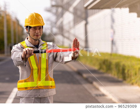 A man in work clothes directing traffic 96529309