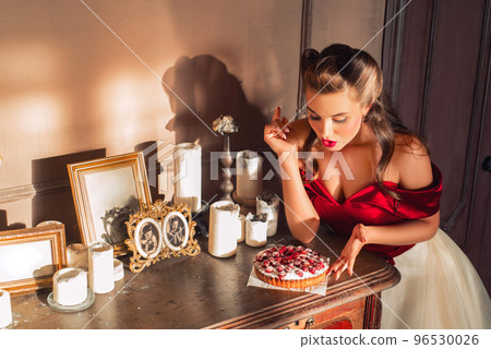 Pretty pin-up girl eats cake in retro interior. Temptation concept 96530026