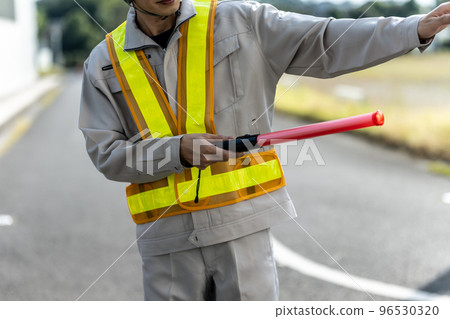 一個穿著工作服的男人在指揮交通 一個穿著工作服的男人在指揮交通 96530320